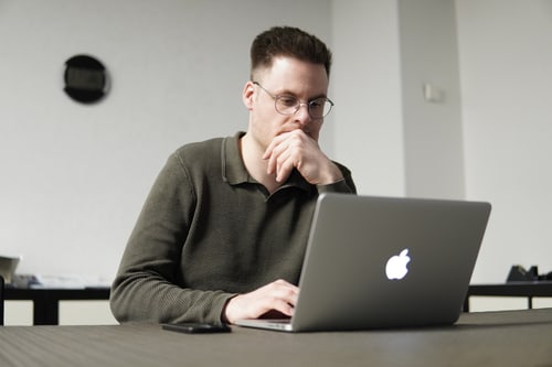 Mann arbeitet konzentriert am Laptop.