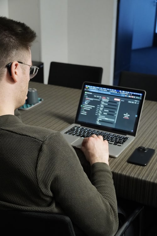 Mann arbeitet an einem Laptop mit Code auf dem Bildschirm.
